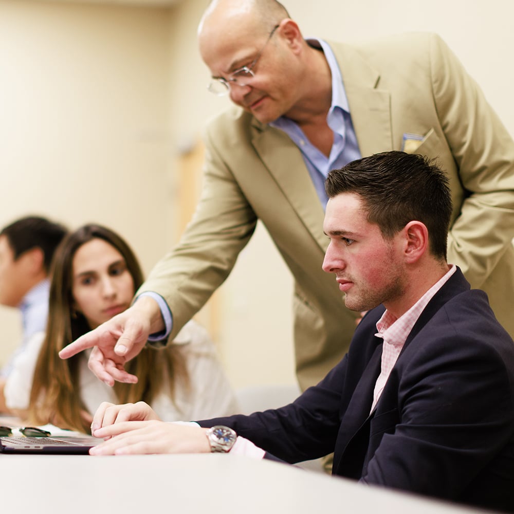 A professor works one on one with a student in class.